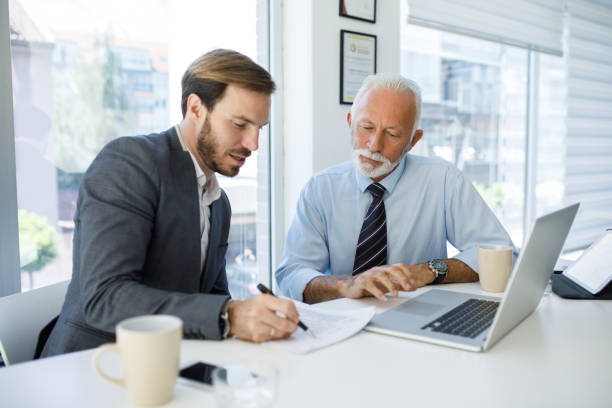 Young businessman cooperating with experienced colleague in the office